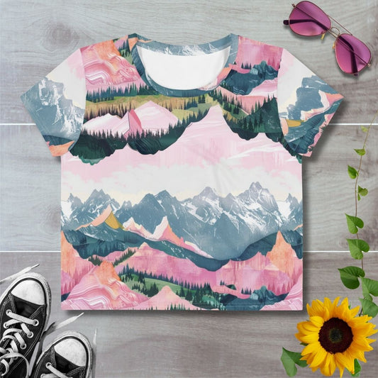 Women's all over print cropped t-shirt. Layered pink mountains and green hillsides with tree lines outlining snowy mountain peaks